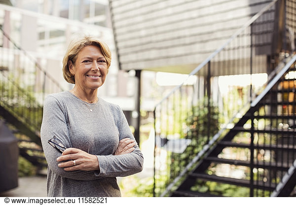 Portrait of confident businesswoman standing arms crossed at office yard