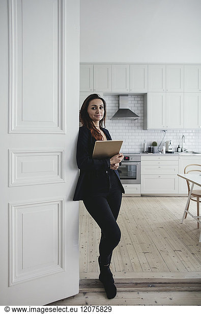 Portrait of confident businesswoman standing at doorway in home office