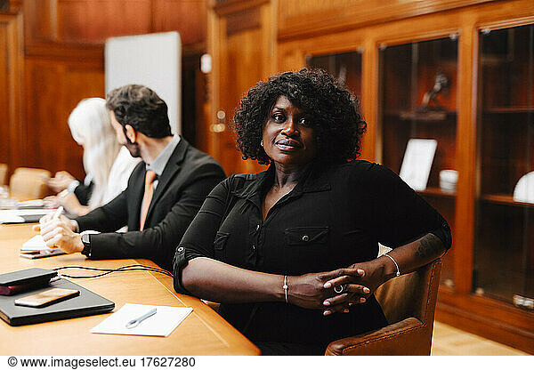 Portrait of confident businesswoman with hands clasped sitting in board room during meeting