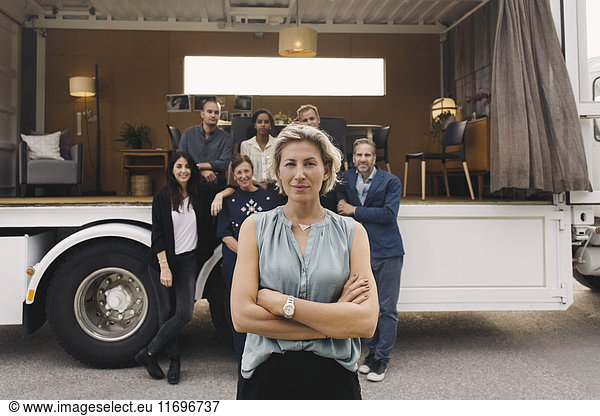 Portrait of confident businesswoman with team and portable office truck in background