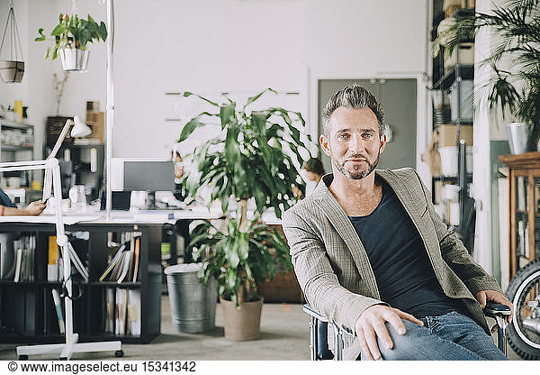 Portrait of confident creative businessman sitting on chair in office