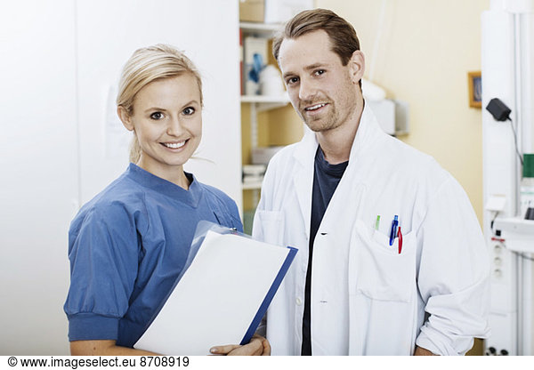 Portrait of confident doctor and nurse with file in hospital