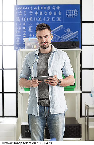 Portrait of confident engineer holding digital tablet in electronic laboratory