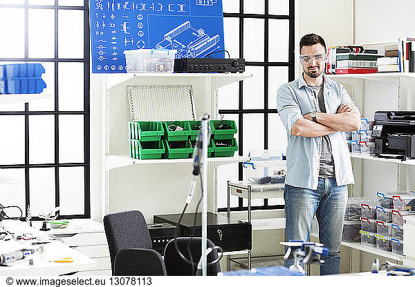 Portrait of confident engineer standing with arms crossed in electronic laboratory