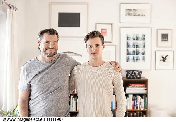 Portrait of confident father and son standing with arms around at new home