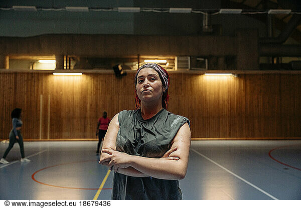 Portrait of confident female athlete with arms crossed at sports court