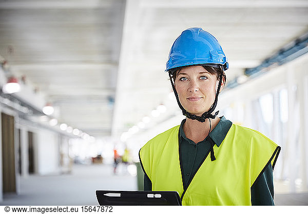 Portrait of confident female construction manager in reflective clothing at site