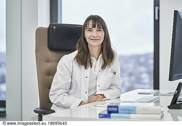Portrait of confident female doctor sitting at desk in medical practice
