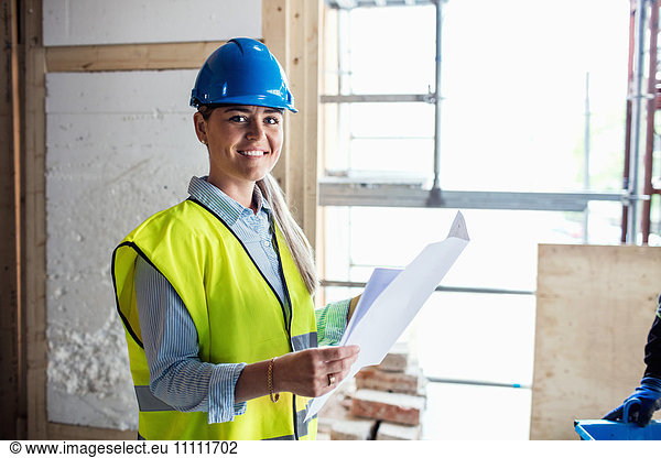 Portrait of confident female manual worker reading document at construction site