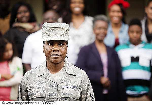 Portrait of confident female soldier standing against family