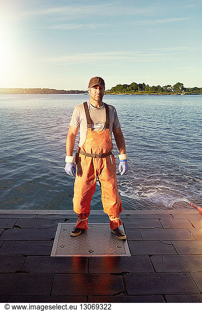 Portrait of confident fisherman standing on pier