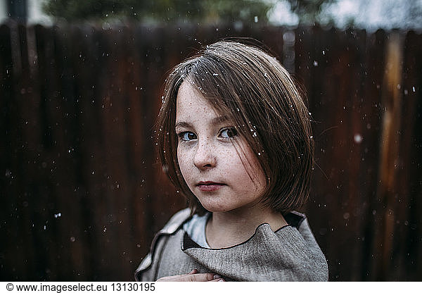 Portrait of confident girl at backyard during snowfall
