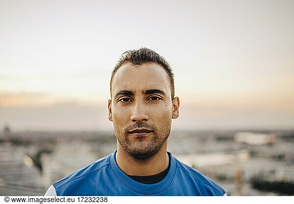 Portrait of confident male athlete against sky during sunset