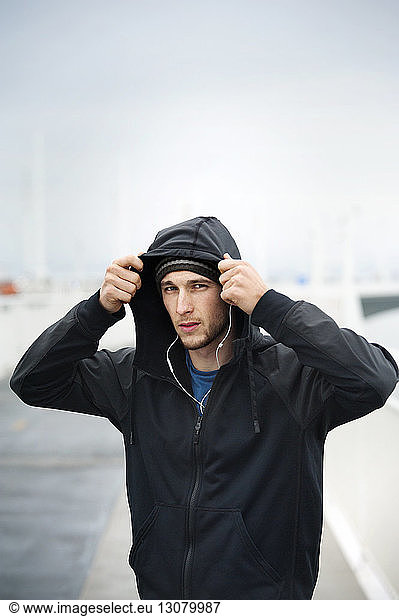 Portrait of confident male athlete wearing hooded jacket on Bay Bridge