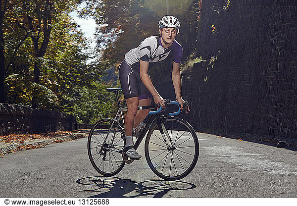 Portrait of confident male athlete with bicycle on road