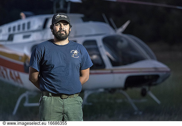 Portrait of confident male helitack standing against helicopter