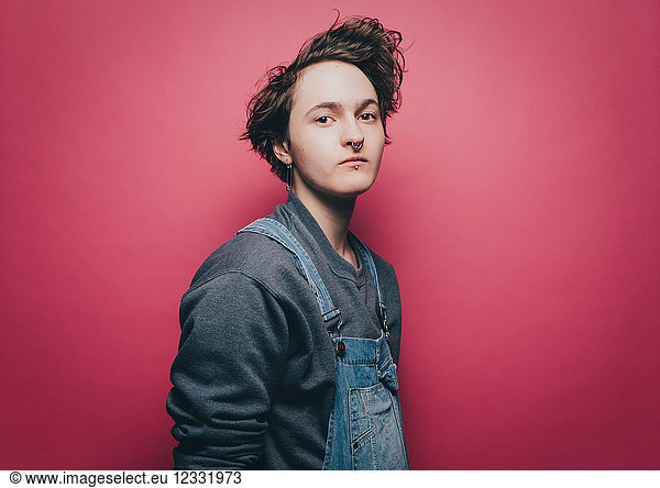 Portrait of confident male hipster standing against pink background