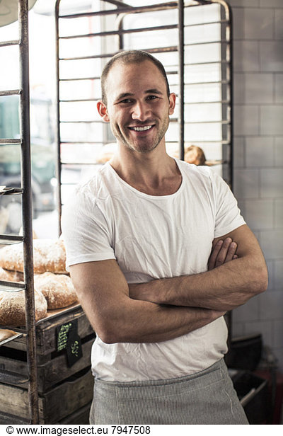 Portrait of confident male owner standing arms crossed in bakery
