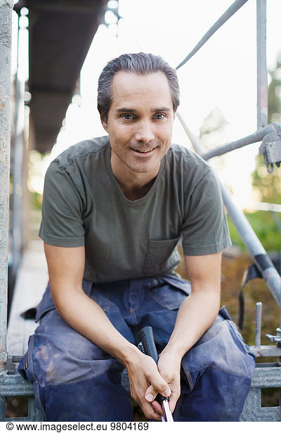 Portrait of confident man sitting outside house being renovated