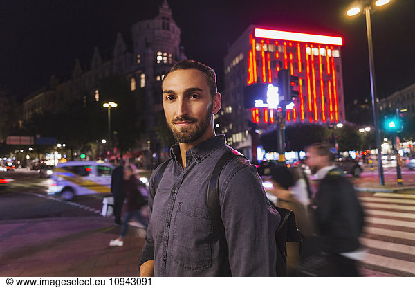 Portrait of confident man standing on city street at night