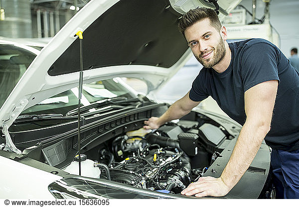 Portrait of confident man working on car in modern factory