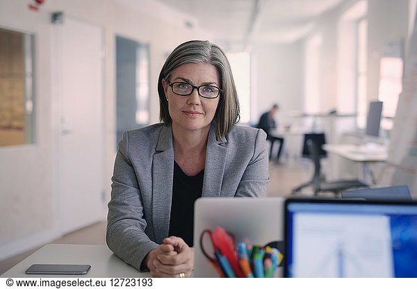 Portrait of confident mature businesswoman sitting at desk in office