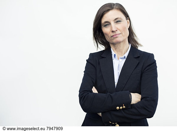 Portrait of confident mature businesswoman standing arms crossed against wall