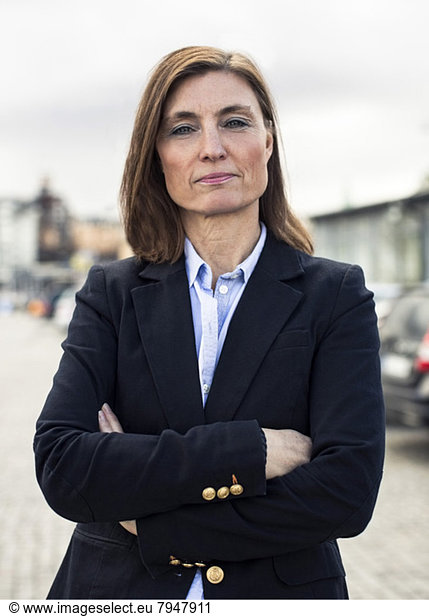 Portrait of confident mature businesswoman standing arms crossed on street