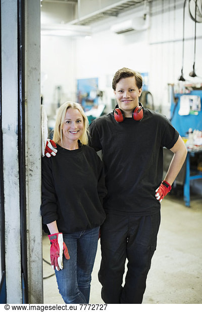 Portrait of confident mechanics standing together at auto repair shop