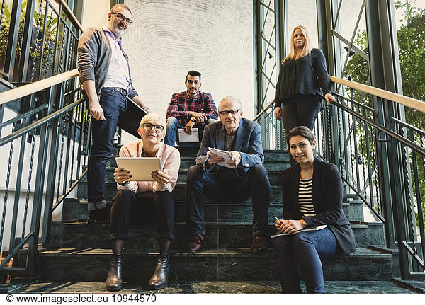 Portrait of confident multi-ethnic business people on stairway in creative office
