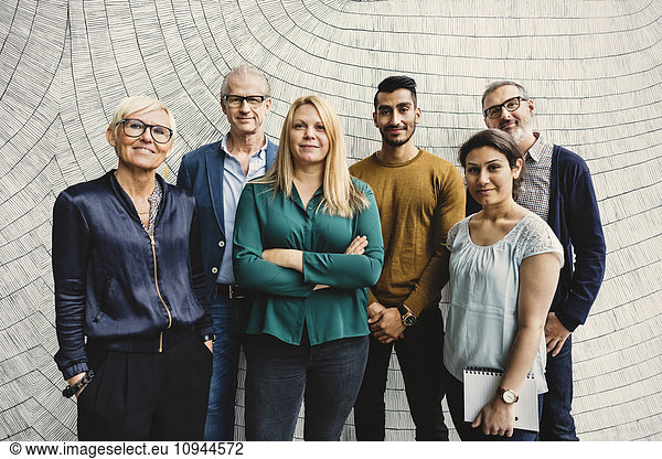 Portrait of confident multi-ethnic business people standing against wall in office
