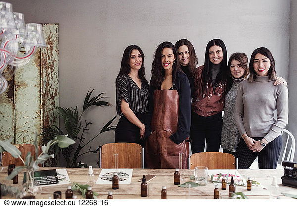 Portrait of confident multi-ethnic female colleagues standing against wall at perfume workshop