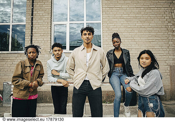 Portrait of confident multiracial young friends in front of wall