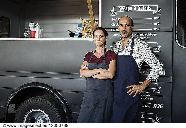 Portrait of confident owners standing against food truck