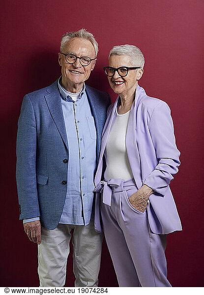 Portrait of confident senior couple against purple background