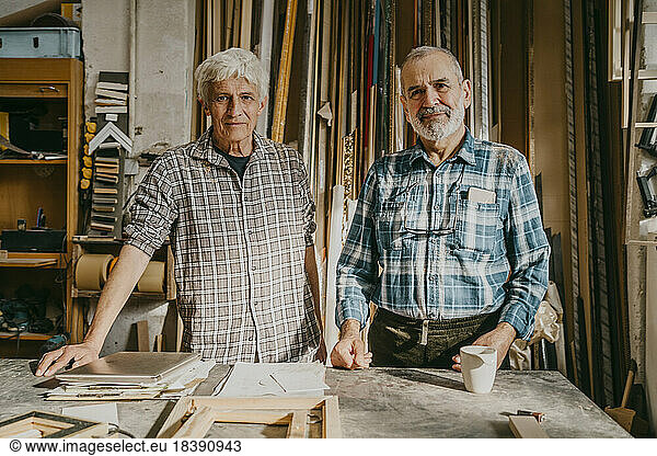 Portrait of confident senior male entrepreneurs standing at carpentry workshop