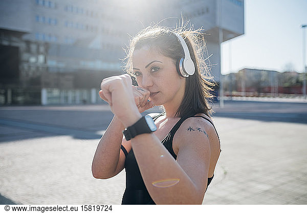 Portrait of confident sporty young woman with headphones in the city