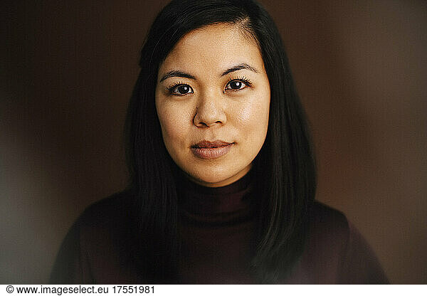 Portrait of confident woman against brown background