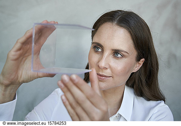 Portrait of confident woman looking at transparant cube