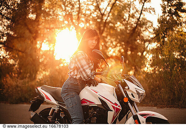 Portrait of confident woman sitting on motorcycle on country road