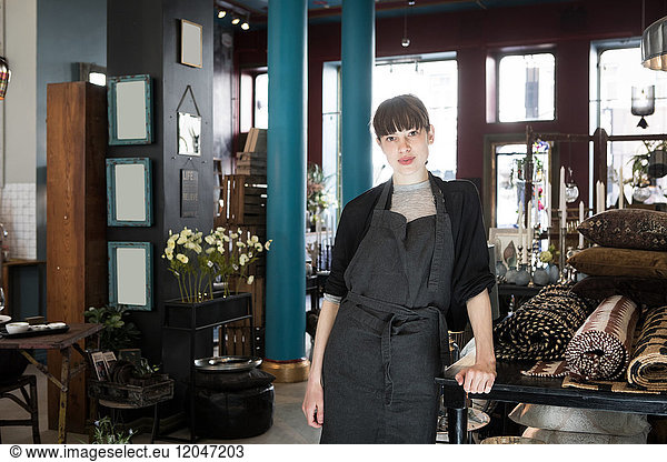 Portrait of confident young female owner standing at store