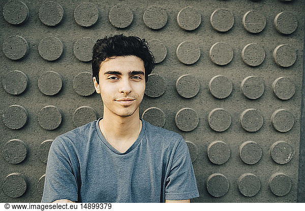 Portrait of confident young man standing against wall