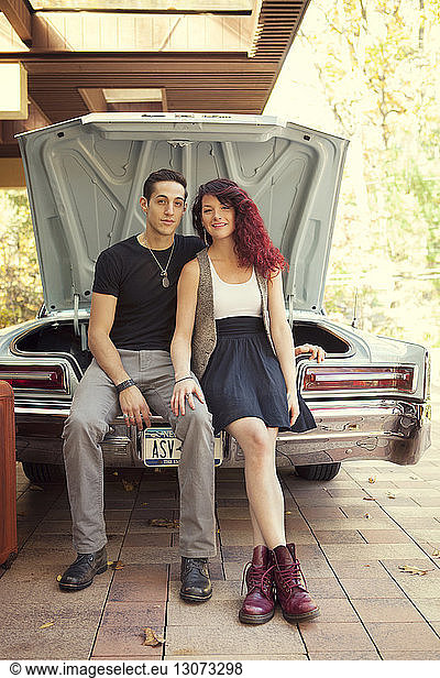 Portrait of couple sitting in car trunk