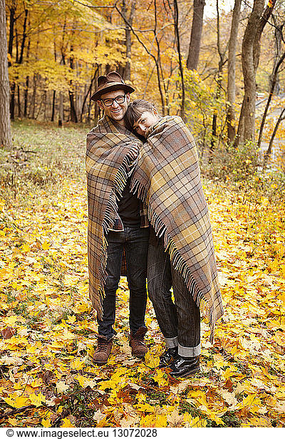 Portrait of couple wrapped in blanket while standing on field