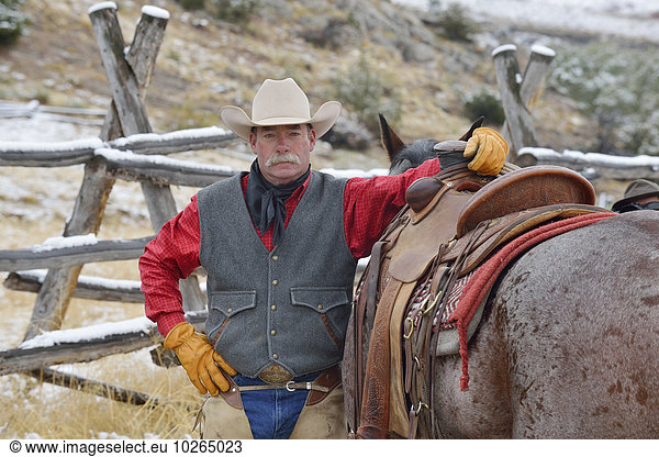 Portrait of Cowboy Standing near Horse  Rocky Mountains  Wyoming  USA