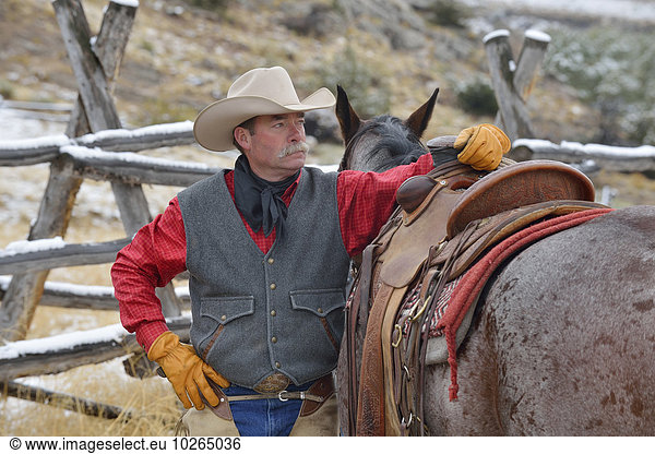 Portrait of Cowboy Standing near Horse  Rocky Mountains  Wyoming  USA