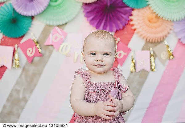 Portrait of cute baby girl against decoration at birthday party