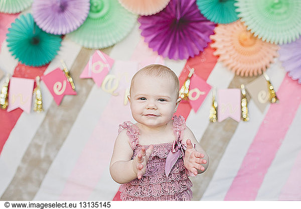 Portrait of cute baby girl clapping at birthday party