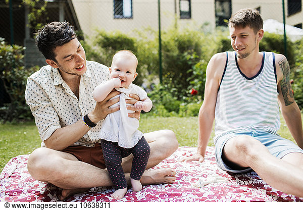 Portrait of cute baby girl with gay couple at yard