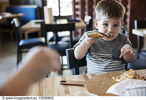 Portrait of cute boy eating pizza at restaurant